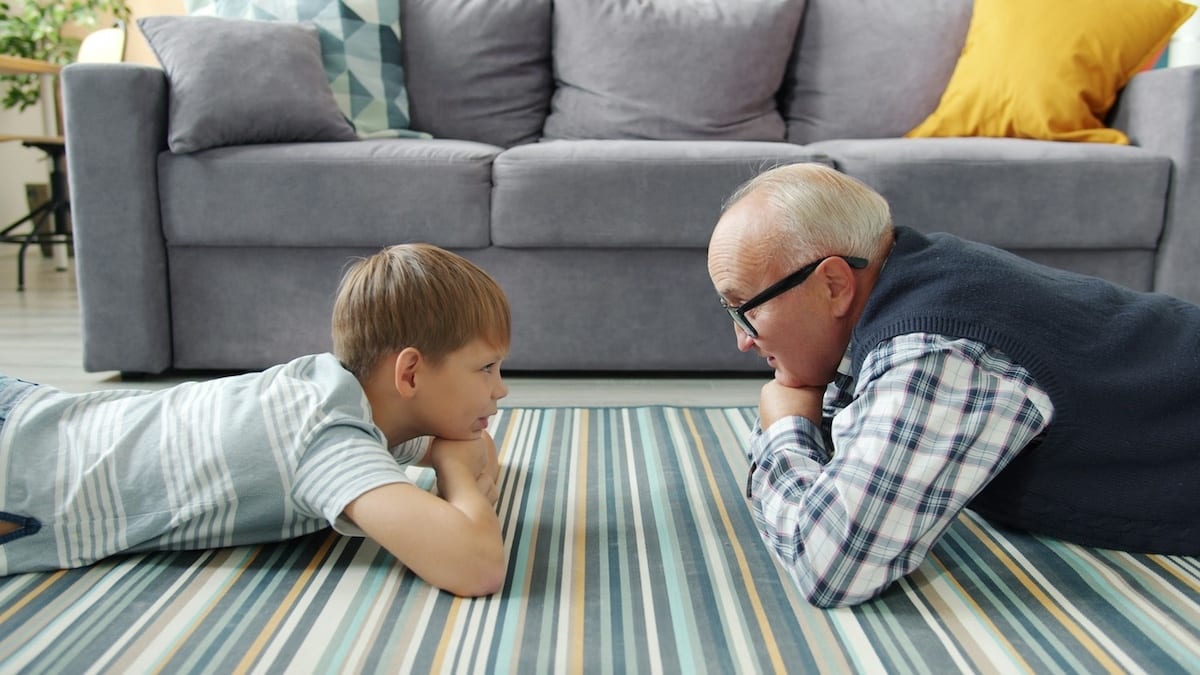grandfather and grandson looking at eachother while lying on the floor of a living room